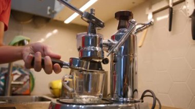 Adam sabah içecek bir fincan hazırlanması için modern çelik kahve makinesi filte sahibi ayarlar
