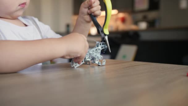 Serious little baby boy repara la construcción meccano con pinzas de aguja-nariz — Vídeos de Stock