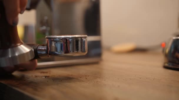 Barista taps the filter holder full of coffee with tamper press. Close up shot — Stock Video