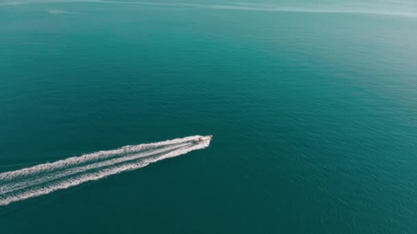 Imbarcazione a motore galleggia in infinito mare blu. L'acqua increspata splende al sole. Colpo aereo — Video Stock