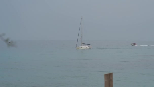 Парусная яхта и моторная лодка плывут по спокойному синему морю. Медленное движение — стоковое видео