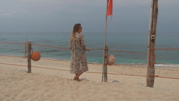 Eftertänksam kvinna står nära rep stängslet på snady beach. Stormen kommer från havet — Stockvideo