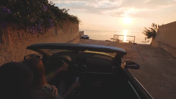 Жінка парки кабріолетом автомобіля біля пляжу для дивлячись на гарний захід сонця над морем — стокове відео