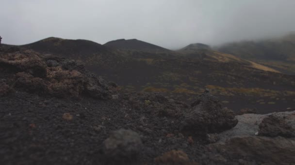 Черные камни на безжизненных вулканических склонах. Низкие серые облака — стоковое видео