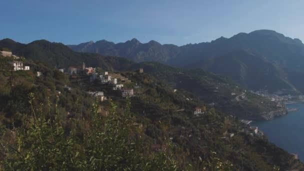 Lattari-Berge über blauem Meer. Morgen an der hügeligen Küste mit Bäumen und Häusern. Schwenkschuss — Stockvideo