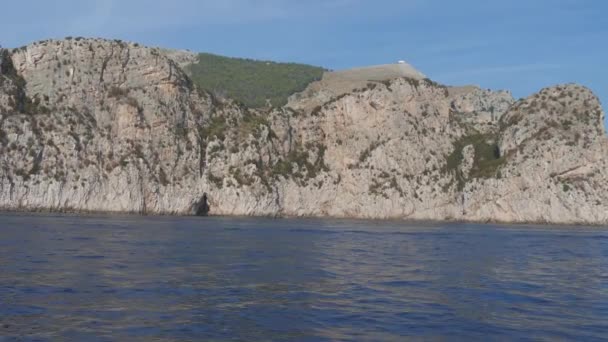 Passeio de barco rápido ao longo penhasco rochoso íngreme sobre o mar azul no dia ensolarado. Punta Campanella, Itália — Vídeo de Stock