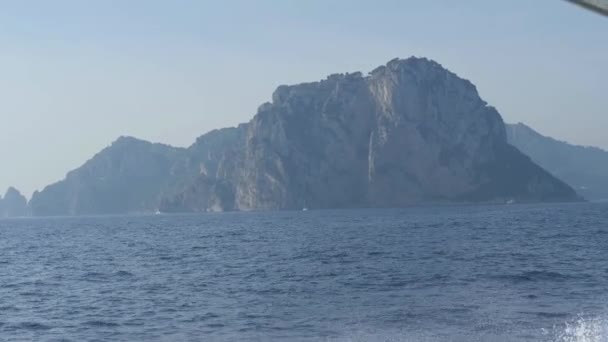 Steile klip op oevers van Capri. Berg over de blauwe zee. Boot komt voor het eiland. Monte Tiberio, Italië — Stockvideo