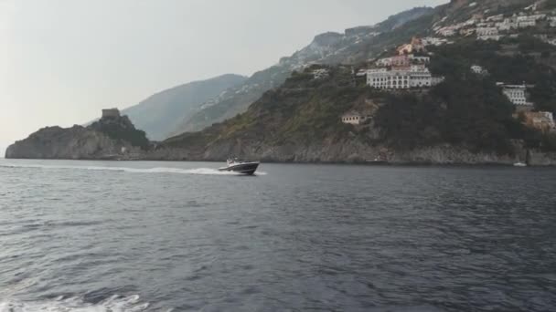 Moderne snelle motorboot drijvers langs heuvelachtige kust van het schiereiland van Sorrento, Italië — Stockvideo