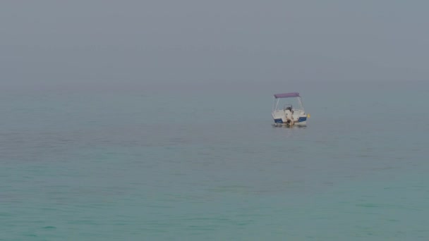 Kis motorcsónak lehorgonyozva leng a szelíd hullámok, a kék tenger — Stock videók