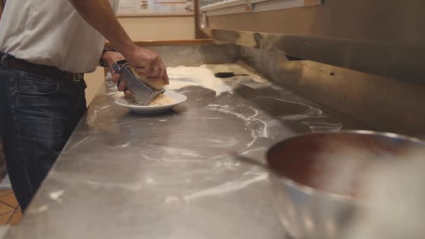 남자는 강판으로 하드 치즈를 격자. 요리사 전문 주방에 작성 하 게 — 비디오