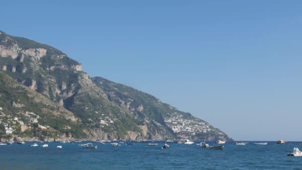 Der Berg erhebt sich über dem blauen Meer mit vielen Wasserfahrzeugen an seiner Oberfläche. positano, italien — Stockvideo