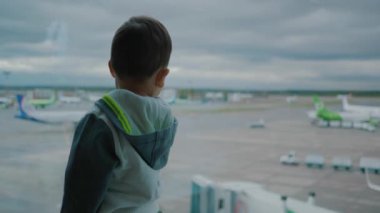 Havaalanında erkek bebek kalkış için bekler ve destek araçları pencereden görünüyor