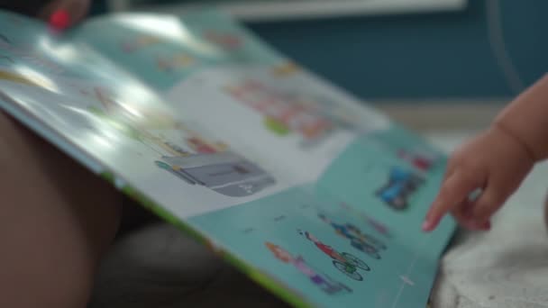 Baby ukazuje prstem na výkres cyklista v ilustrované knize — Stock video