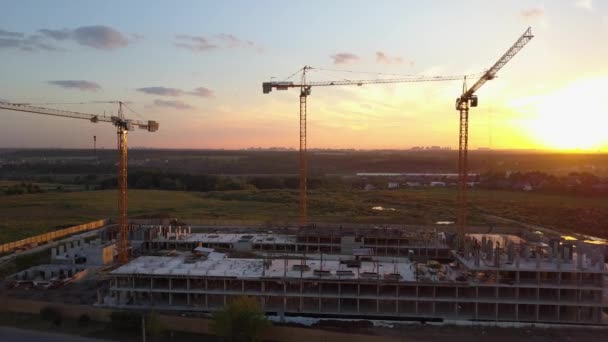 Повітряний знімок будівельного майданчика з кранами проти заходу сонця — стокове відео
