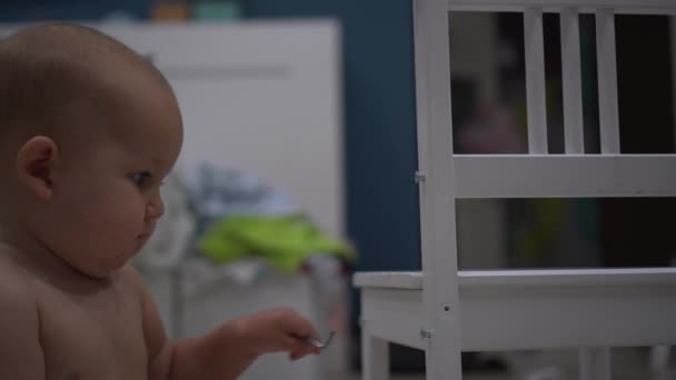 Kleine baby met een tool probeert aan te scherpen een schroef in een stoel — Stockvideo