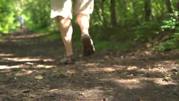 Un uomo cammina su una pista sporca in un parco verde. Primo piano delle gambe nei sandali sportivi — Video Stock