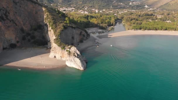 Small boat enters the river mouth near natural rocky arch. Aerial shot of Palinuro coastline, Italy — Stock Video