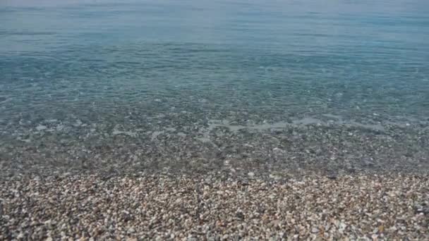 Zee golven wassen kiezelstrand. Gladde stenen in kristal helder water. Slow motion — Stockvideo