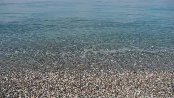 Mare onde lavaggio spiaggia di ghiaia. Pietre lisce in acqua cristallina. Rallentatore — Video Stock