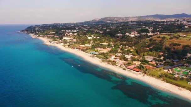 Dois pedalos brancos flutuam no mar azul-turquesa ao longo da praia de areia com resorts. Fotografia aérea da costa italiana — Vídeo de Stock