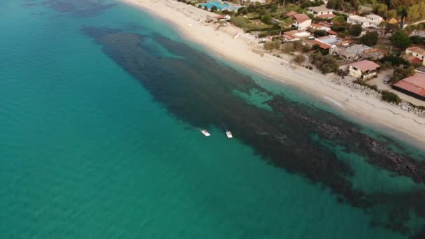 Dos botes de pedal flotan en aguas turquesas transparentes junto a la playa de arena del resort italiano. Disparo aéreo — Vídeo de stock