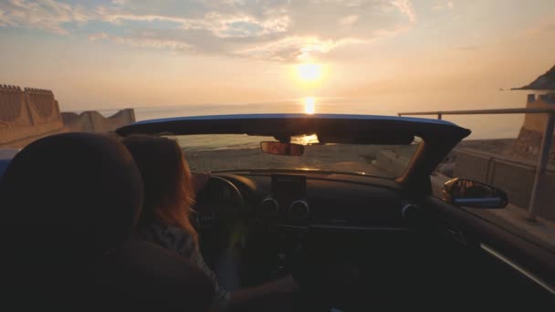 Mulher canta e dança no lugar de motorista em carro conversível. Pôr do sol sobre o mar — Vídeo de Stock