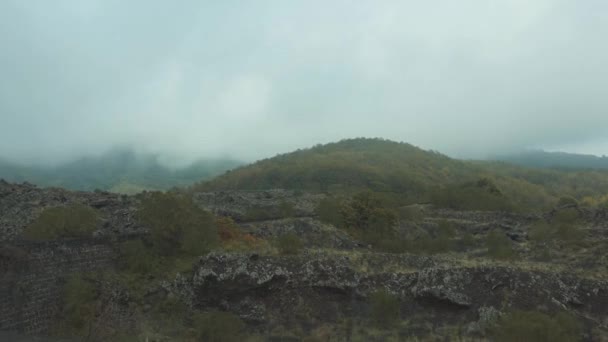 Déplacement en voiture par des pentes rocheuses. Sommets couverts de nuages gris. Vue de fenêtre latérale 