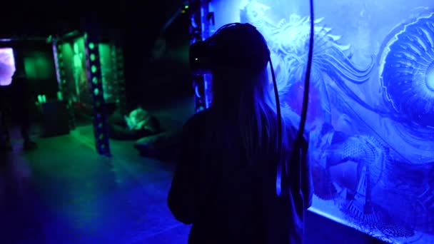 Woman in virtual reality headset against picture on a wall in blue light — Stock Video