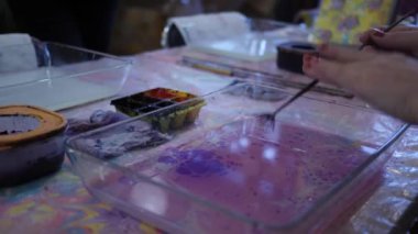 Sanatçı su yüzeyine mor mürekkep sıçratıyor. Ebru veya kağıt bilye tekniği