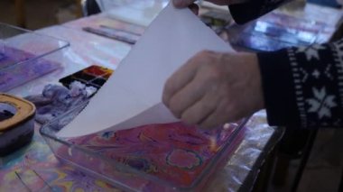 Bir kumaş parçası soyut bir tasarımı aktarmak için mürekkep lekeleri ile suya bağlanır. Kağıt bilye sanatı