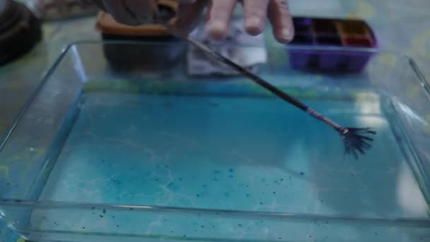 Künstler sprüht blaue Farbe auf Wasseroberfläche. Eru- oder Papiermarmoriertechnik — Stockvideo