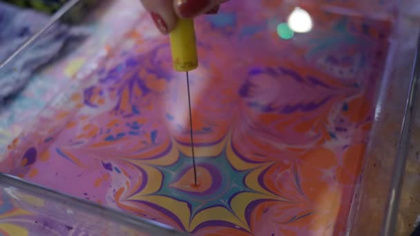 Thin stick moves in water and makes star on its surface. Paper marbling in pink color — Stock Video