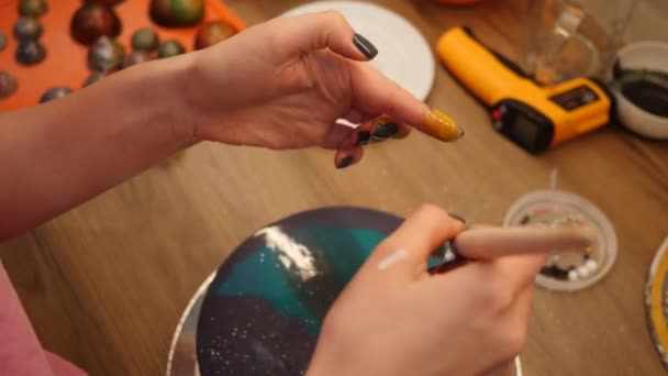 Konditorin verziert blauen Kuchen mit Spritzern Lebensmittelfarbe. Farbtropfen vom Pinsel — Stockvideo