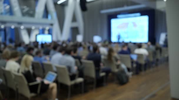 People seat in front of screen. Lecture in a modern space. Unfocused scene — Stock Video