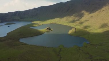 Caldeirao 'nun yeşil yamaçlarında güneş ışığı ve bulut gölgeleri. Corvo Havalimanı, Azores