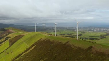 Yeşil adanın üstündeki bulutlu gökyüzü. Rüzgar türbinleri enerji üretir. Terceira Havalimanı, Azores