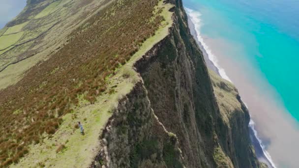 Mulher caminha ao longo da borda de penhasco íngreme de vasto vulcão extinto. Aerila de Caldeirao, Corvo, Açores — Vídeo de Stock