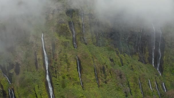 高い山の急な斜面に緑の植物の間の水のストリーム。雲が上を覆っている。フローレスの空中,アゾレス諸島 — ストック動画