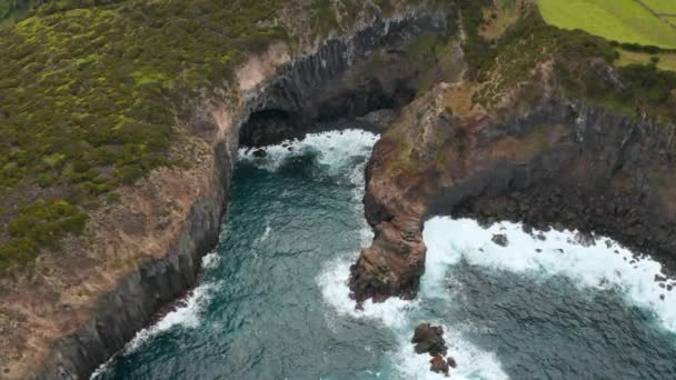 Grot in rotsachtige klif gewassen door schuimende zee golven. Luchtfoto van Terceira, Azoren — Stockvideo