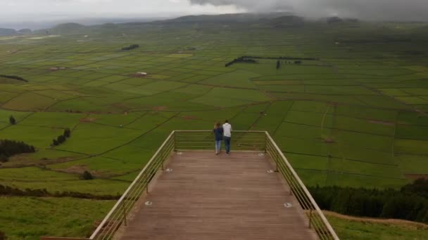 Pár ember a Serra do Cume nézőpontból. Zöld völgy mezőkre osztva a hegy lábánál. Terceira levegője, Azori-szigetek — Stock videók