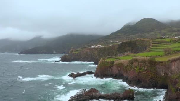 Rocky coastline and ocean waves. Storm clouds above green island. Aerial of San Miguel, Azores — Stock Video