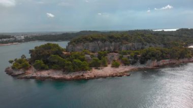 Adriyatik Denizi kıyısındaki kayalık pelerinin etrafında uçuyor. Hırvatistan 'ın Istria kentindeki yeşil orman ve kayalar