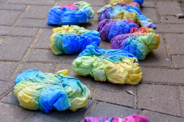 Still-wet tie-dye T-shirts compressed with rubber bands after being painted by a group of teenagers in a tie-dye party