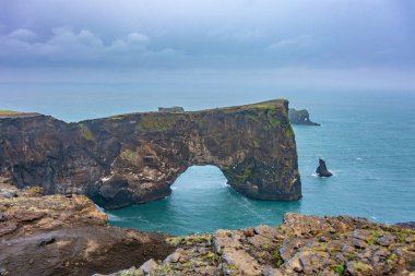 Şaşırtıcı tek sıra halinde bazalt oluşumları, tonozlu bir covern ve deniz kaya yığınları görünür plaja ses İzlanda'daki Reynisfjara siyah kum plaj
