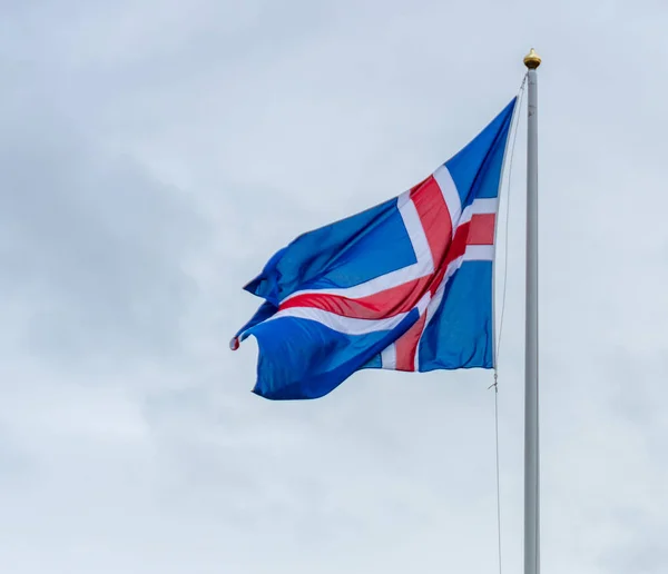 Iceland flag of red and white cross on blue backgroumd hanging proudly in the windy Icelandic weather