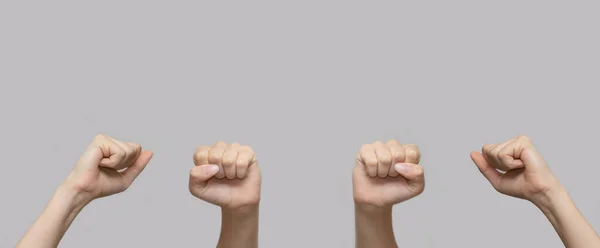 Weiße Menschenhände mit erhobenen Fäusten in der Luft auf grauem, isoliertem Hintergrund. Großaufnahme, Banner, Kopierraum. Das Konzept von Protest, Gewalt und Kampf. — Stockfoto