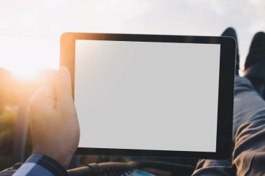 Tatil yaşam tarzı kavramı, Closeup tablet bilgisayar ve ayakları üzerinde dağ manzaralı, sıcak gün batımı filtre efekti bakan balkon kullanarak adam