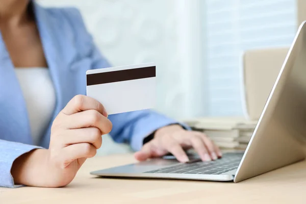 Mano que sostiene la escritura de la tarjeta de crédito en el teclado del ordenador portátil para el concepto de comercio electrónico de compras en línea — Foto de Stock
