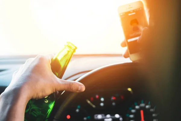 Drinking and driving ,man drinking alcohol and using mobile phone while driving car ,concept drive safely while using a cell phone or drunk alcohol