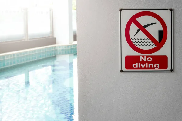 No diving sign at the poolside warning on blurred swimming pool Stock Image